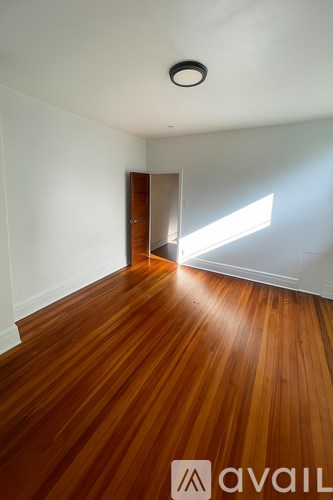 A room with wooden floors and a door leading to another room.