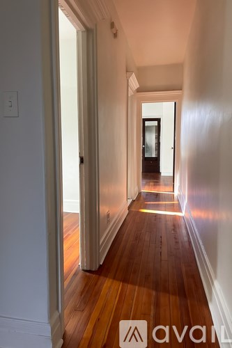 A long hallway with wood floors and white walls.