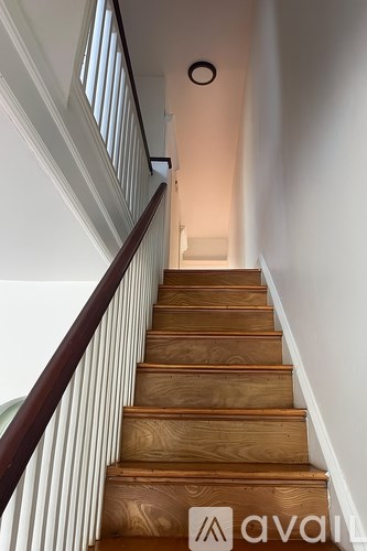 A wooden staircase with a white wall on the side.