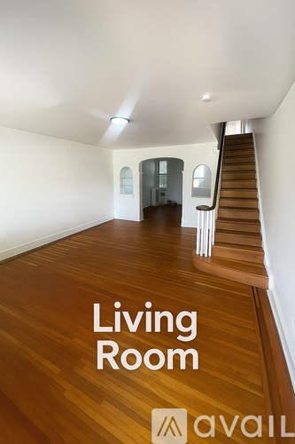 A living room with wooden floors and a staircase.