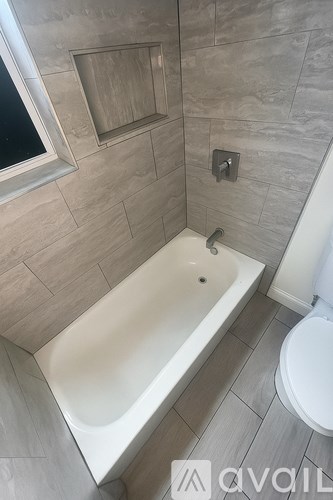 A bathroom with a tub, toilet, and window.