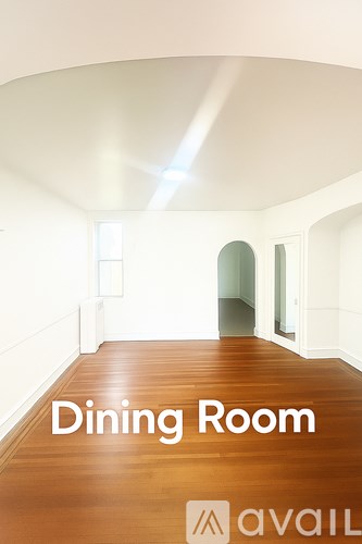 A dining room with wood floors and white walls.