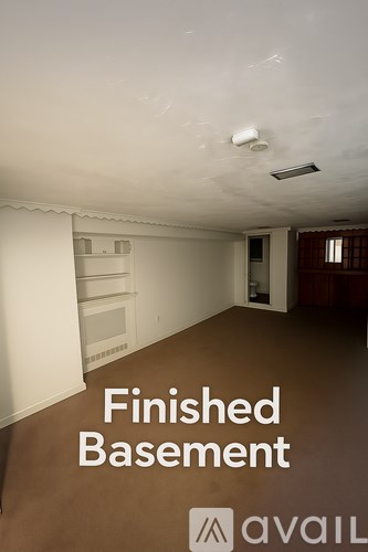 A finished basement with a white ceiling and a brown floor.