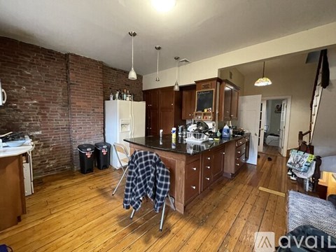 A kitchen with wooden floors and a brick wall.