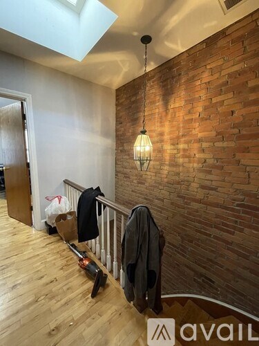 A room with a wooden floor and a brick wall with a hanging light fixture.
