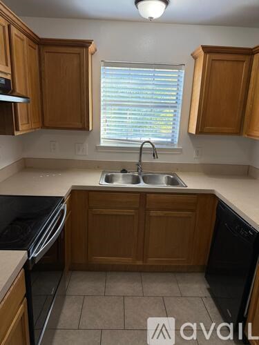 A kitchen with wooden cabinets and a black dishwasher.