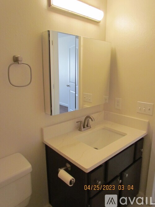 A bathroom with a toilet, sink, and mirror.