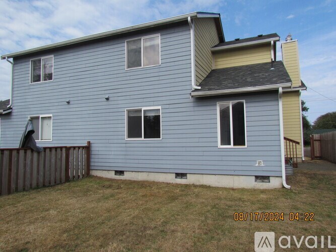 A blue house with a grey roof and a wooden fence.