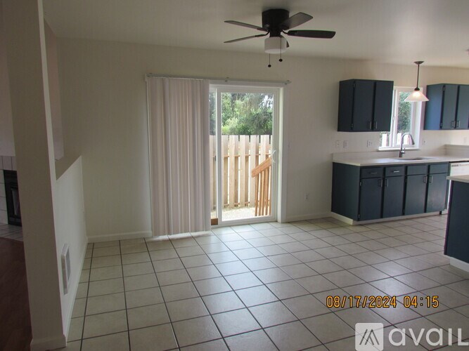 A room with a ceiling fan and a sliding glass door leading to a deck.