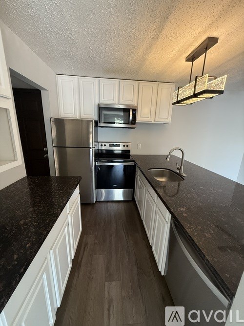 A kitchen with white cabinets and a black countertop.