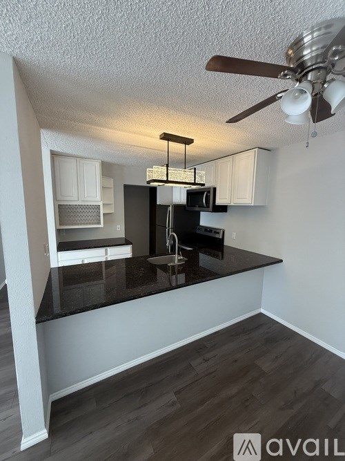 A kitchen with a black countertop and white cabinets.