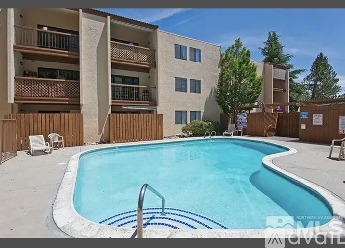 A swimming pool in front of a building with apartment balconies.