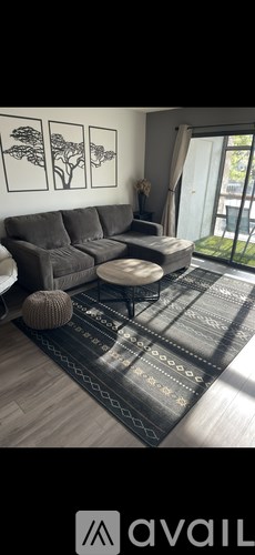 A living room with a grey sofa and a rug.