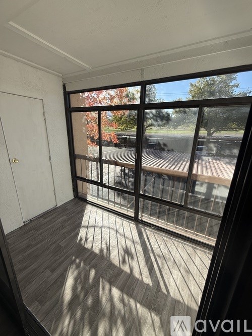 A balcony with a white door and a view of a tree and a building.