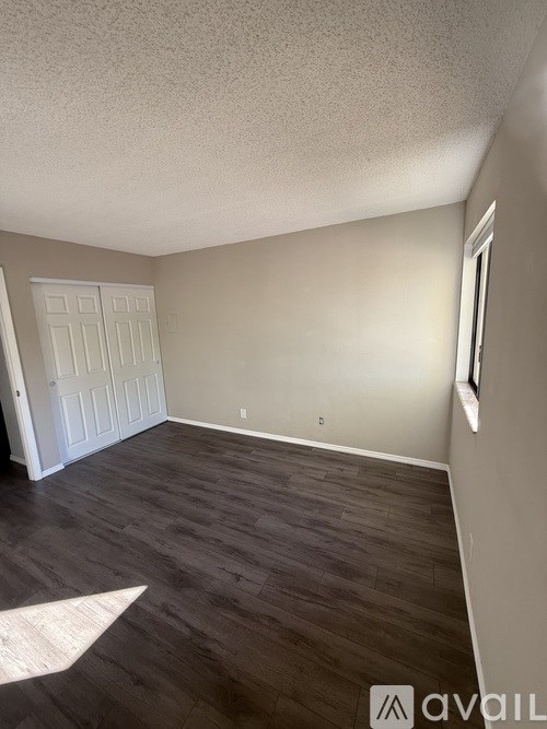 A room with a white door and wooden flooring.