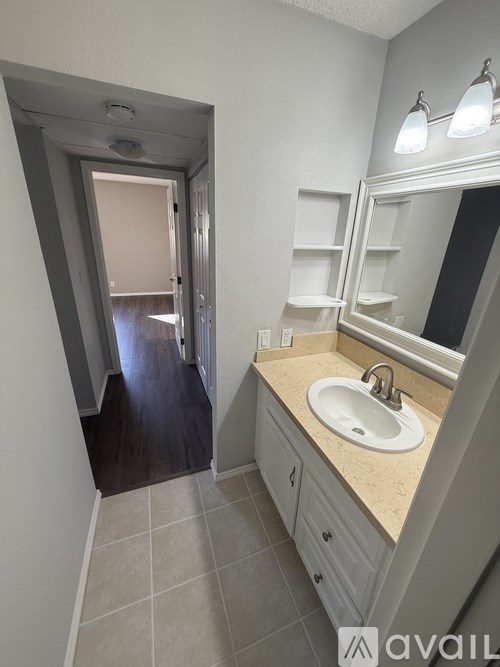A bathroom with a sink, mirror, and a doorway leading to another room.