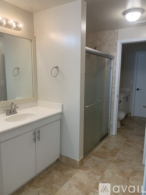 A bathroom with a sink, mirror, and shower.