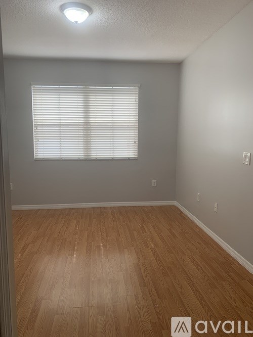 A room with wooden flooring and a window with blinds.