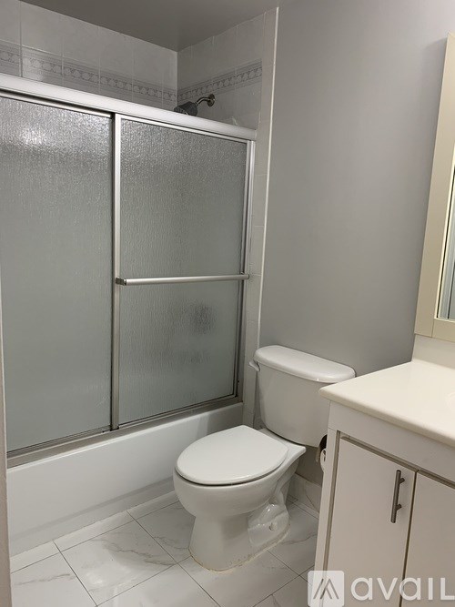 A white toilet sits in a bathroom next to a walk-in shower.