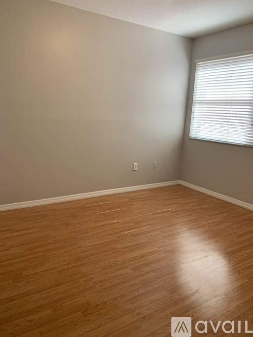 A room with wooden flooring and a window with blinds.