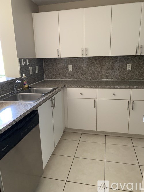 A kitchen with white cabinets and a black dishwasher.