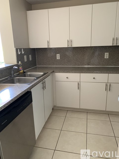 A kitchen with white cabinets and a black dishwasher.
