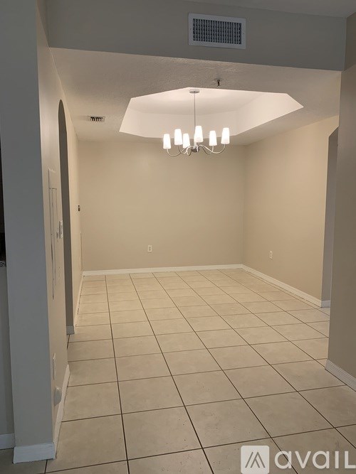 A room with a chandelier and tiled flooring.