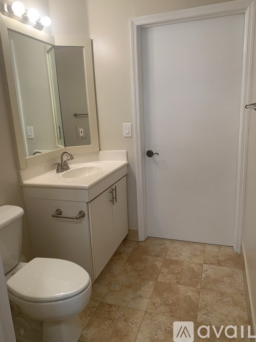 A bathroom with a toilet, sink, and mirror.