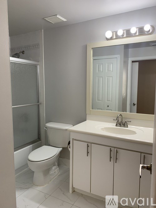 A bathroom with a toilet, sink, and mirror.