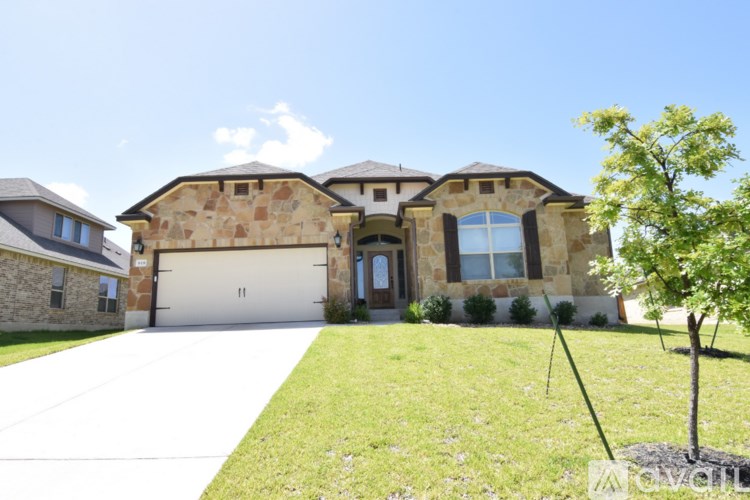 A large house with a garage and a tree in front.