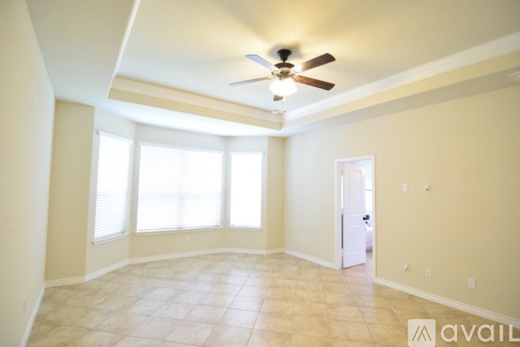 A room with a ceiling fan and a door leading to another room.