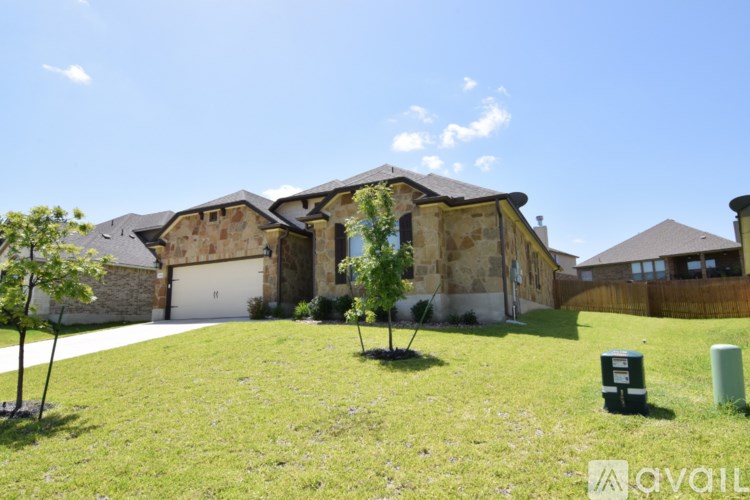 A house with a stone facade and a large lawn in front.