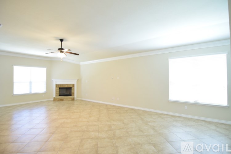 A spacious room with a fireplace and a ceiling fan.