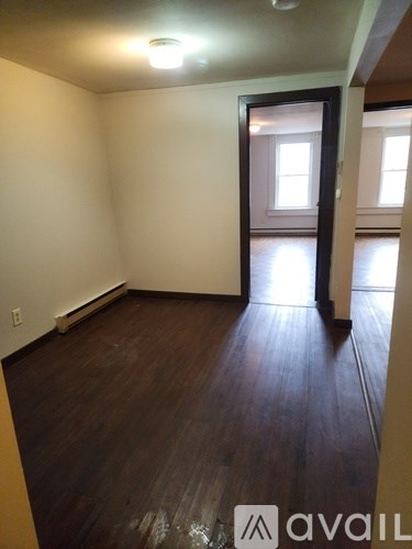 A room with wooden floors and a door leading to another room.