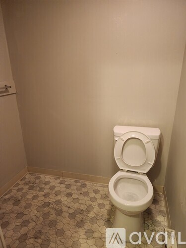 A white toilet in a bathroom with a tiled floor.