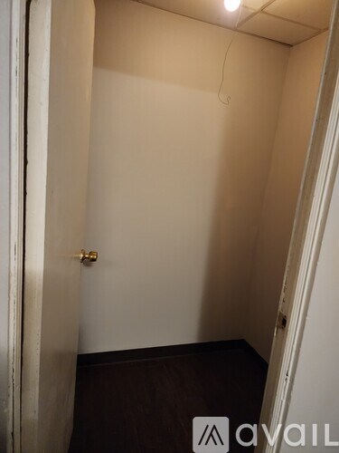 A small, empty room with a door on the left and a wall on the right.