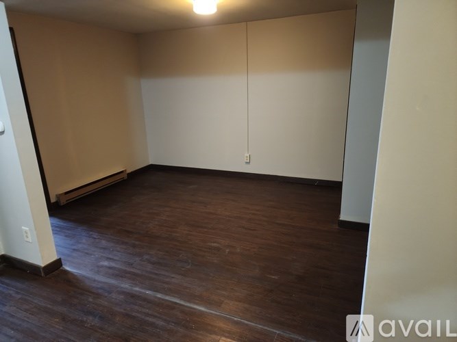 A room with wooden flooring and a white wall.