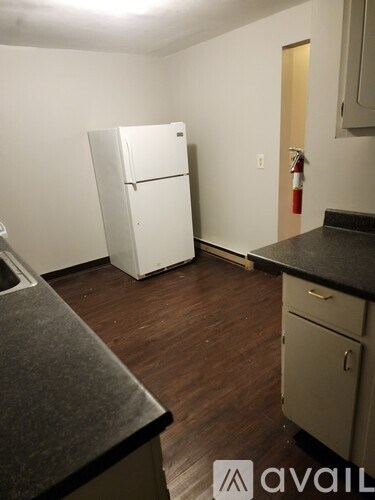 A kitchen with a white fridge and a black counter top.