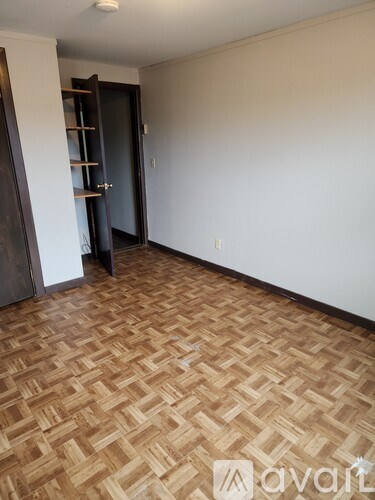 A room with a wooden floor and a door with a shelf.