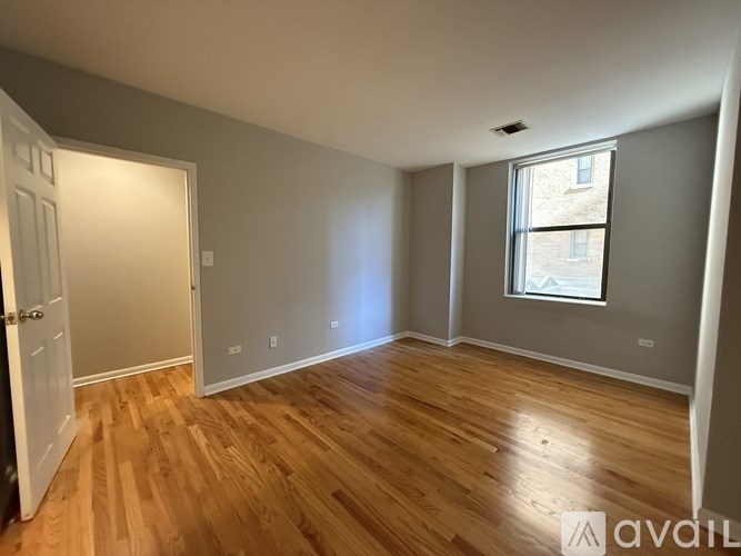 A room with wooden floors and a window showing a building outside.