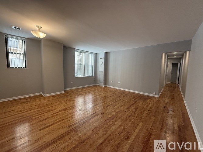 A room with wooden flooring and a window with blinds.