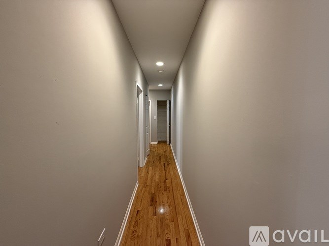 A long hallway with wooden floors and white walls.
