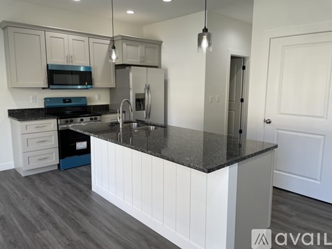 A kitchen with white cabinets and a black countertop.