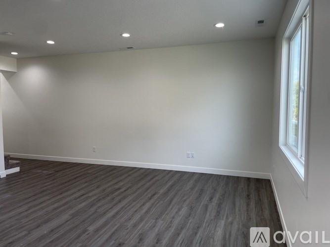 A room with wooden flooring and a window on the right side.