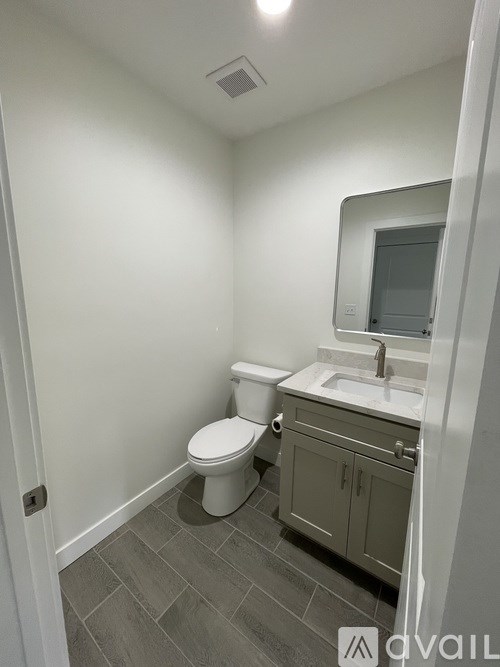 A small bathroom with a toilet, sink and cabinet.