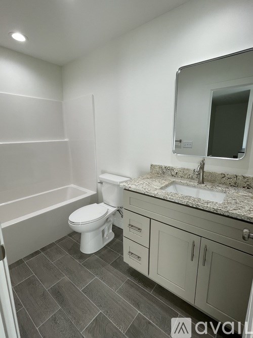 A bathroom with a toilet, sink, and mirror.