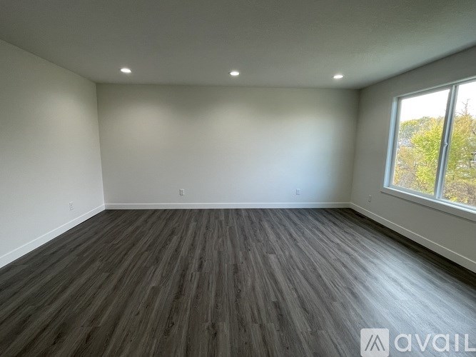 A room with wooden flooring and a window showing trees outside.
