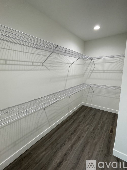 Empty walk-in closet with wooden floors and wire shelving.