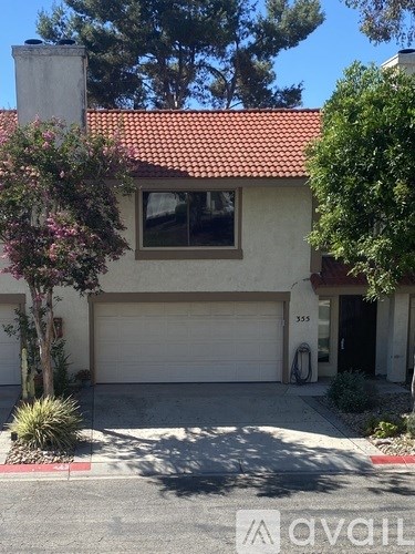 A house with a garage and a tree in front.