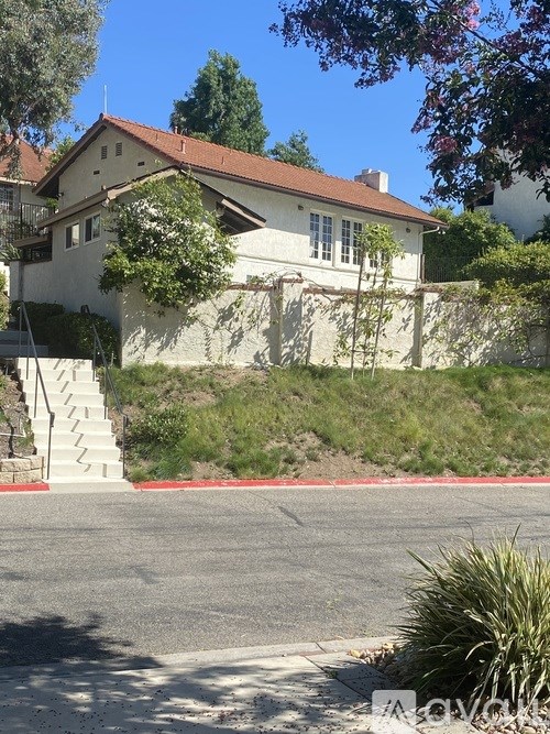 A house with a red roof and a white wall with a staircase leading to the entrance.